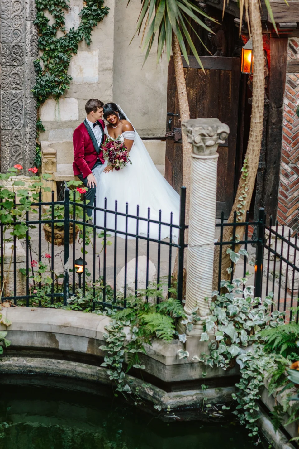 A newlywed couple sharing a quiet moment among ivy-covered stonework.